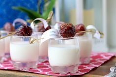 three glasses filled with milk and cherries on a table