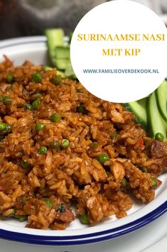 a white plate topped with rice covered in meat and veggies next to cucumbers