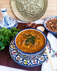 a bowl of soup is sitting on a table with other dishes and utensils