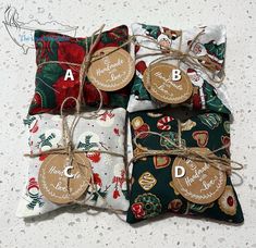 four christmas themed pillows tied together with twine and tags on the front, sitting next to each other