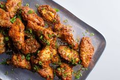 some fried food is on a plate with garnishes and seasoning sprinkles