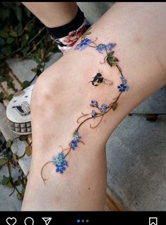 a woman's leg with blue flowers and vines tattoo on the lower part of her leg