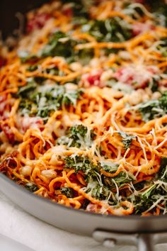 a pan filled with pasta and spinach covered in cheese