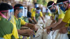 several people wearing masks and protective clothing are sorting items at a recycling center in the philippines