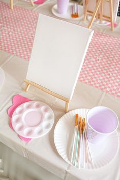 an easel, paintbrushes and paper plates on a table