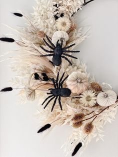 a wreath made out of dried flowers and spider decorations