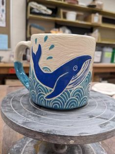 a blue and white whale mug sitting on top of a wooden table in a shop