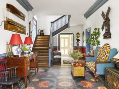 a living room filled with lots of furniture next to a stair leading up to a second floor