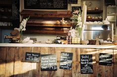 a restaurant with wooden walls and chalkboard menus on the wall, along with flowers in vases