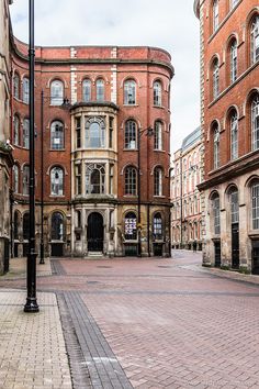 an old brick building in the middle of a cobblestone street with tall buildings on both sides