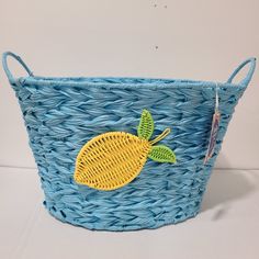 a blue basket with a yellow lemon embroidered on the front and green leaves in the back