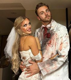 a man and woman dressed up in zombie wedding attire, one holding the other's arm