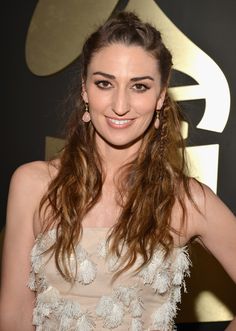 a beautiful young lady posing for the camera in front of a wall with an award on it