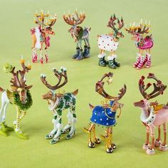 a group of christmas figurines sitting on top of a green floor next to each other