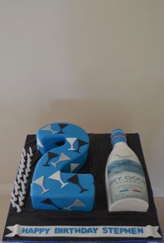 a birthday cake with blue and white items on it, including a bottle of water