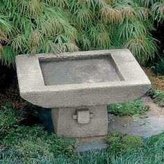 a concrete bird bath sitting in the grass