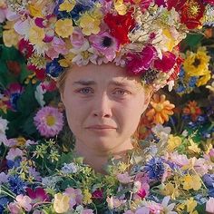 a woman with flowers on her head in the middle of a field full of wildflowers