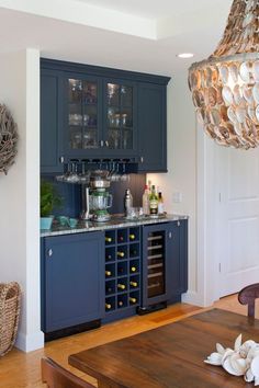 a kitchen with blue cabinets and wine rack in the center, next to a dining room table