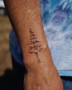 a man's arm with a tattoo on it that has a pine tree on it