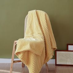 a yellow blanket sitting on top of a wooden chair