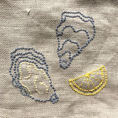 two embroidered faces on a piece of cloth, one is yellow and the other is grey