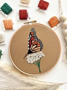 a close up of a butterfly on a piece of cloth with beads and yarn around it