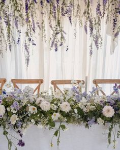 flowers and greenery are arranged on the back of chairs