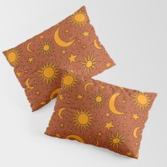 two pillows with sun and moon designs on them, one is brown and the other is orange