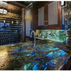 a kitchen counter top with wine bottles in the back ground and lights on above it