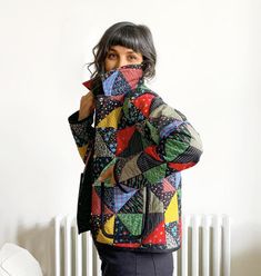 a woman standing in front of a radiator holding her face to her mouth