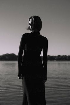 a woman standing in front of the water with her hands on her hips by an open body of water