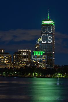 the city skyline is lit up at night with green lights on it's skyscrapers