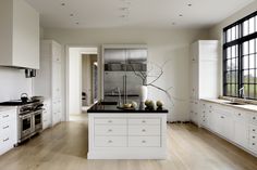 a large kitchen with white cabinets and black counter tops, along with an island in the middle