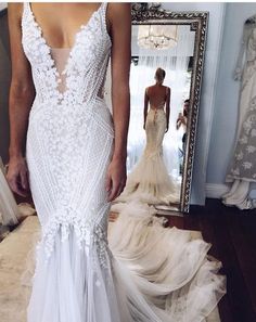 a woman in a white wedding dress looking at herself in the mirror