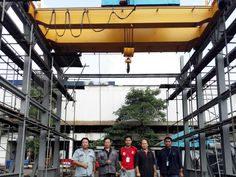 four men standing in front of a large crane