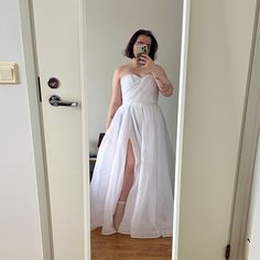 a woman in a white dress taking a selfie