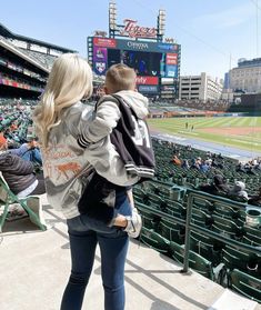 a man and woman are standing in the stands at a baseball game with their arms around each other