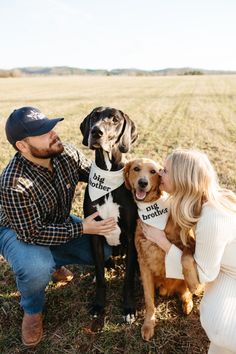 a man and woman sitting next to two dogs