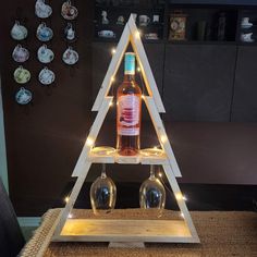 a wooden christmas tree with two wine glasses on the bottom and lights in the middle