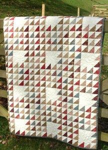 a quilt hanging on a fence in the grass