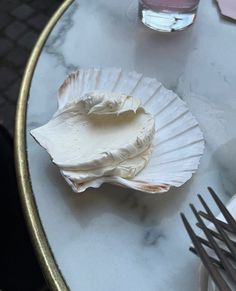 there is a shell on the table next to some forks and spoons in front of it