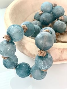 a wooden bowl filled with blue beads on top of a table