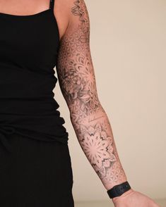 a woman's arm with tattoos on it and a black dress in the background