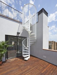 there is a white spiral staircase on the outside of this house with wood flooring