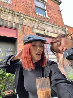 two women standing next to each other near a building with a blender in front of them