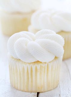 cupcakes with white frosting sitting on a table