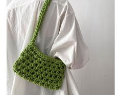 a green crocheted purse hanging from the back of a woman's white shirt