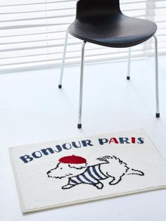 a white rug with the words bonjou paris on it and a black chair next to it