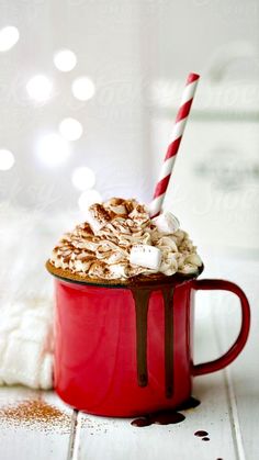 a red mug filled with hot chocolate and marshmallows on top of a white table