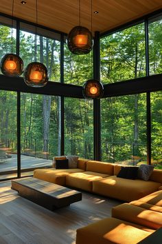 a living room filled with lots of furniture and large windows overlooking the forest outside it